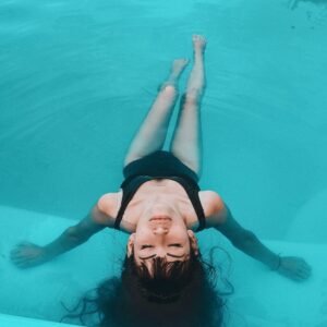 A woman in a black swimsuit floats gracefully in a serene swimming pool.